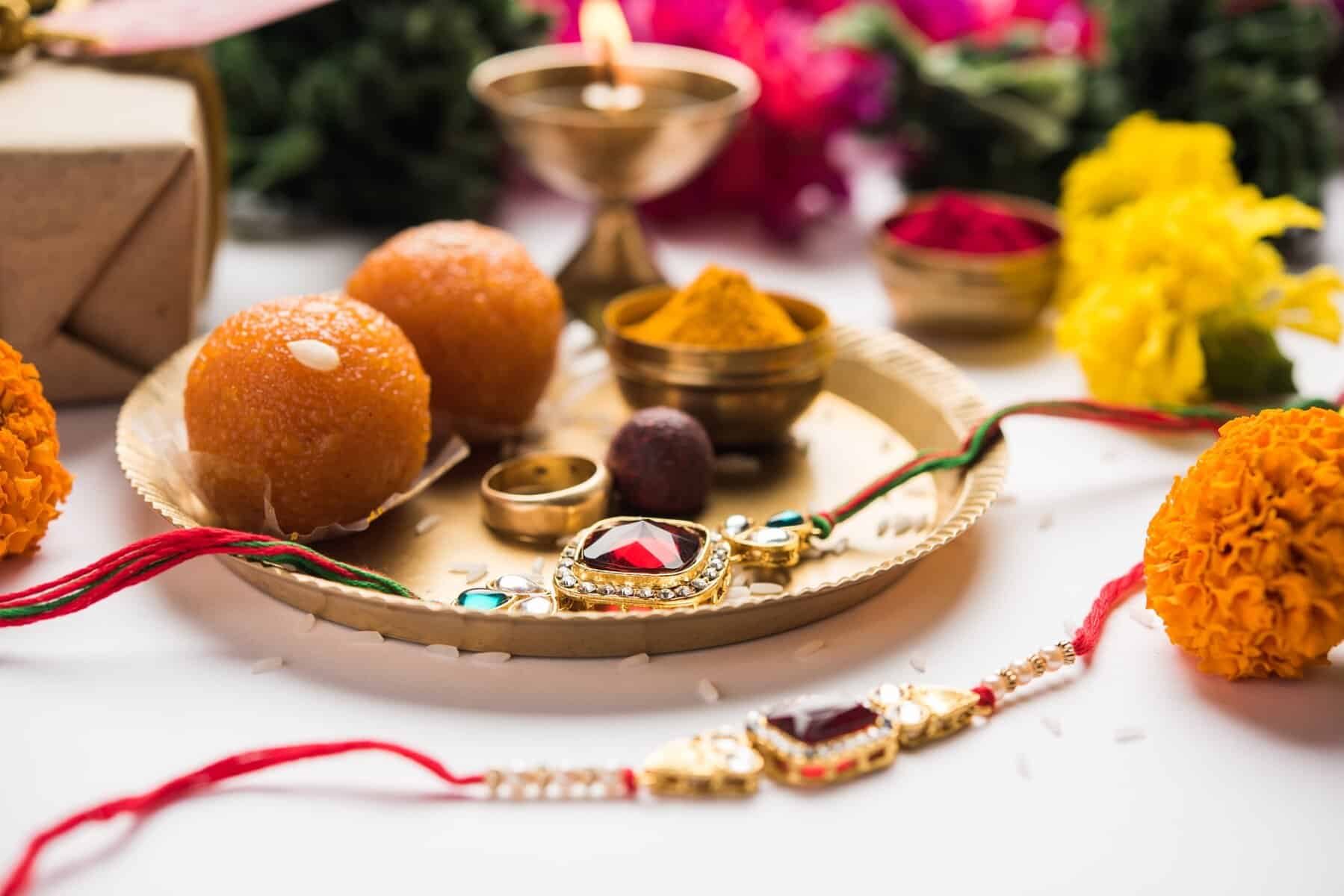 Indian festival Raksha Bandhan with rakhi bracelets, presents, rice and kumkum and sweets in plate